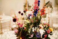 22 a bold wedding centerpiece of violet, pink, yellow, orange and blue blooms including roses, dahlias and allium is wow