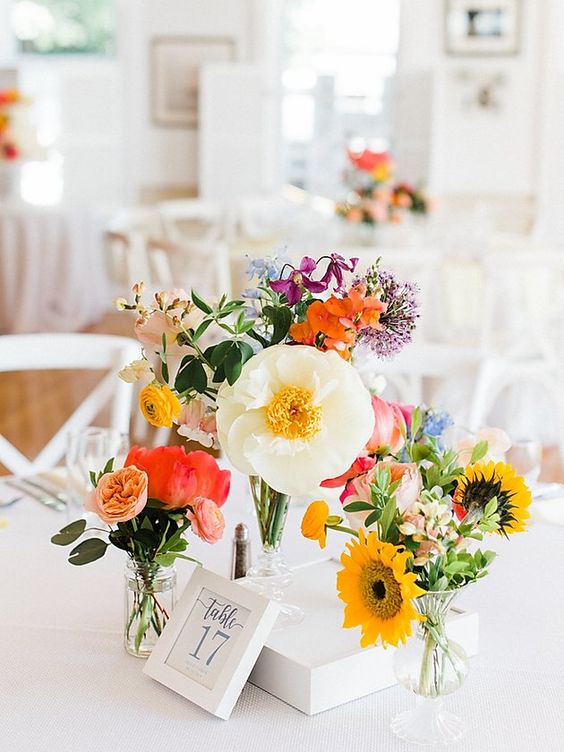 a bright cluster wedding centerpiece with peachy, red, pink, white, yellow blooms including allium is wow