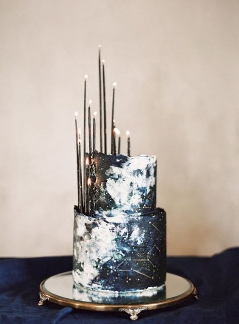 a dark navy and black watercolor wedding cake with constellations and thin black candles brings that wow factor