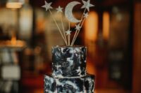 25 a dark watercolor wedding cake topped with silver glitter stars and moon on a shiny silver stand