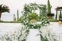 25 a refined wedding aisle done with lots of white delphinium and greenery and a matching green and white wedding arch