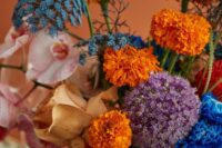 26 a colorful and dimensional wedding centerpiece of a blush bowl, yellow, orange, electric blue blooms including allium