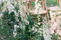 26 a relaxed but chic wedding aisle with greenery, white and blush delphinium and pillar candles is a stunning idea for a backyard wedding