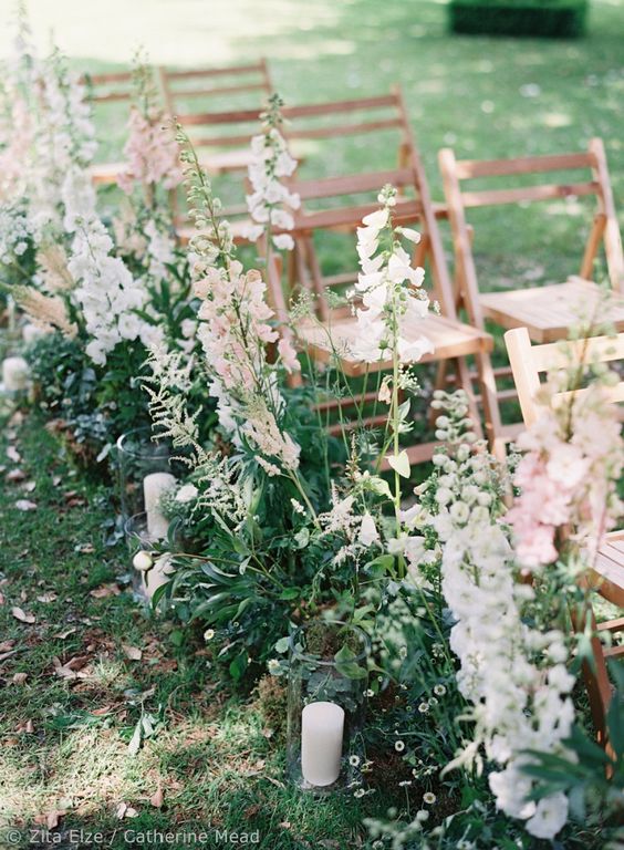 a relaxed but chic wedding aisle with greenery, white and blush delphinium and pillar candles is a stunning idea for a backyard wedding