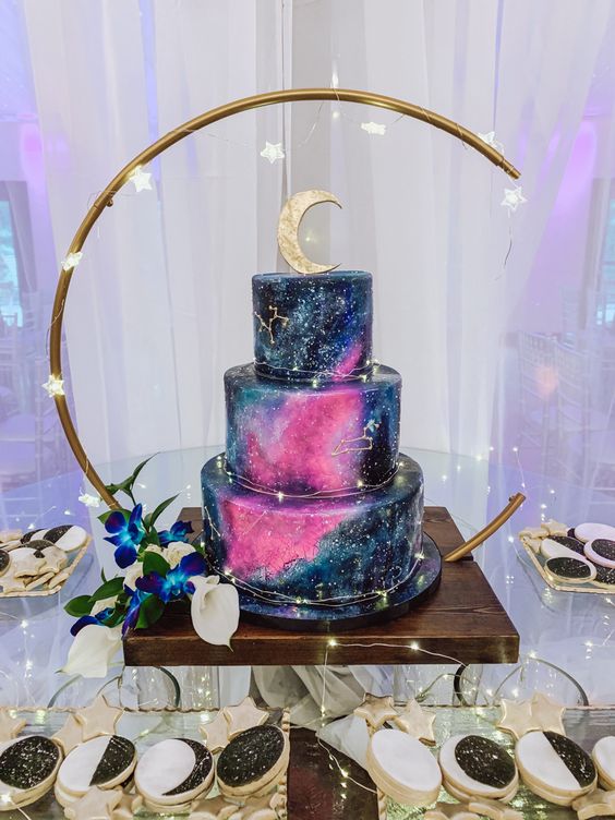 a galaxy-inspired wedding cake with hot pink detailing and gold constellations plus a half moon cake topper is wow