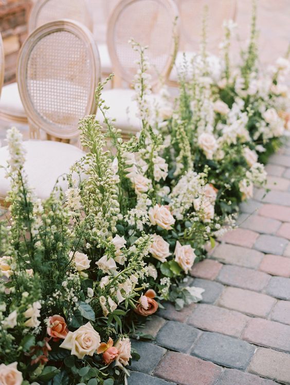 a sophisticated wedding aisle with greenery, creamy and blush roses, greenery and white delphinium is amazing