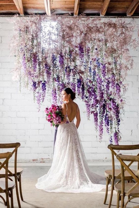 a unique wedding backdrop composed of blush blooms and purple and white delphinium is a lovely solution