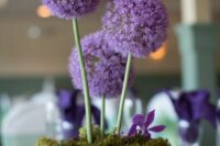 29 a simple and bold wedding centerpiece of a bowl with moss, alliums and purple blooms is a lovely idea for a secret garden wedding