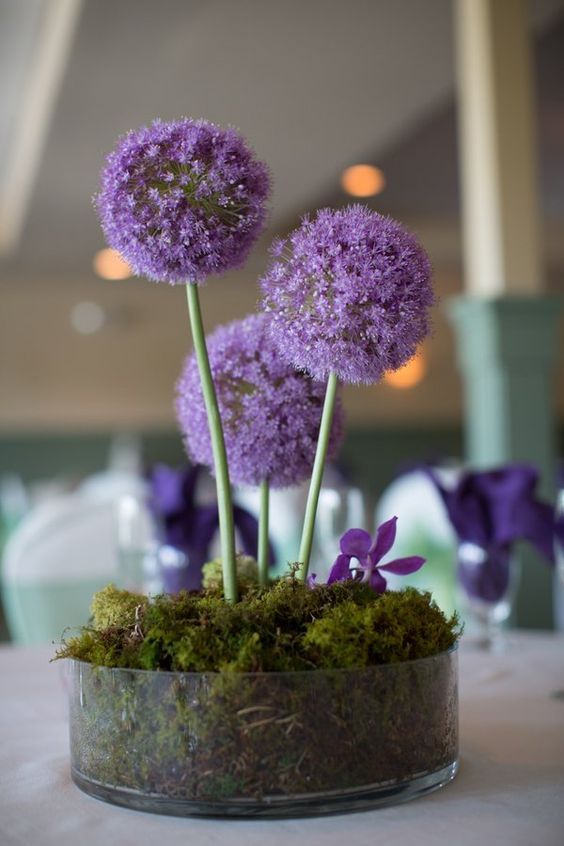 a simple and bold wedding centerpiece of a bowl with moss, alliums and purple blooms is a lovely idea for a secret garden wedding
