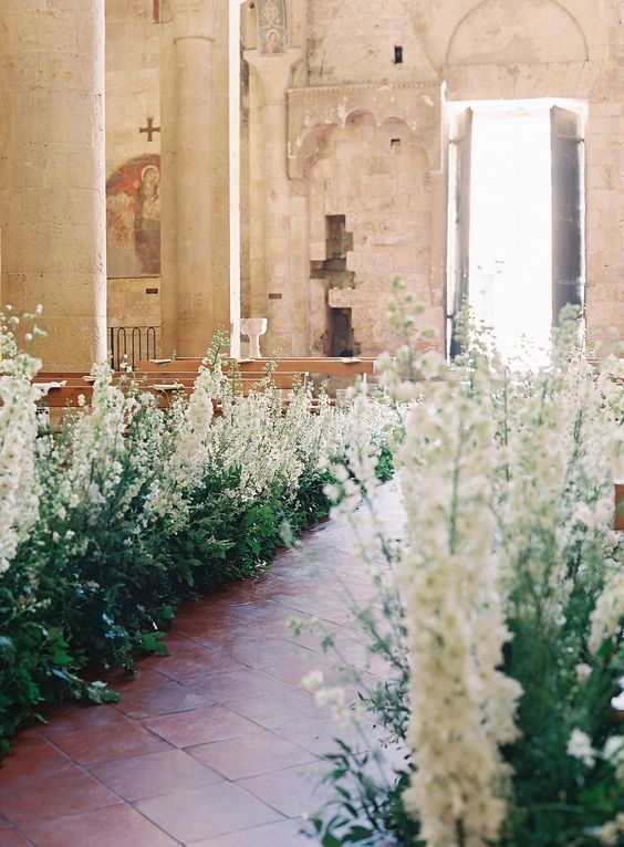 a wedding aisle turned into a wild garden one, with lots of greenery and white delphinium, is a gorgeous idea