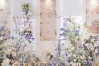 30 an indoor garden-inspired wedding altar made of white and purple delphinium, white blooms and greenery and candles on the floor