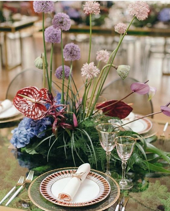 an eye-catchy and dimensional wedding centerpiece of allium and refined tropical blooms and fern is a bold and catchy idea
