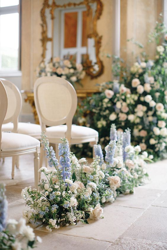 delicate wedding aisle decor with greeneyr, white roses and ranunculus and blue delphinium is a chic and lovely idea