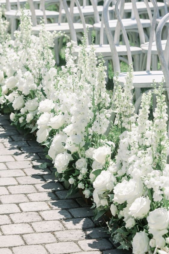 stunning wedding aisle decor done with white roses, greenery and white delphinium is a beautiful and chic idea