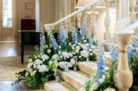 38 wedding stairs decorated with white blooms, blue deliphinium, greenery and pillar candles look amazing