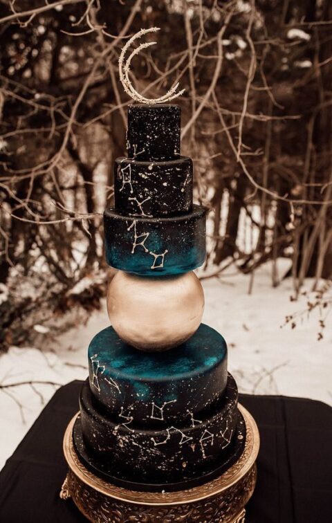 a whimsical constellation wedding cake in black, teal and gold, with catchy tiers and a half moon cake topper