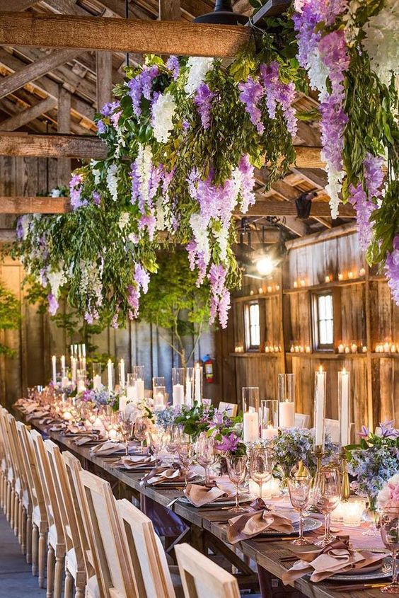 greenery, white and lilac delphinium hanging over the reception table and ones placed on the table make the space magical