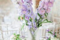 46 a lovely tall wedding centerpiece of white, lilac and blush delphinium and greenery in smaller vases around is cool
