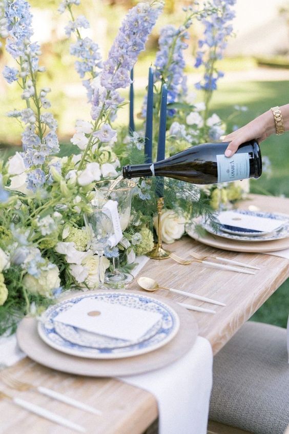 classic wedding table decor done with white and blue delphinium, greenery and blue printed plates is amazing