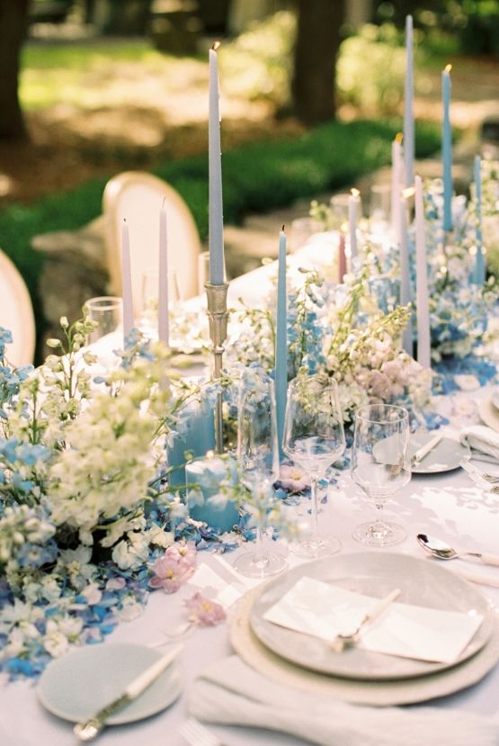 stylish pastel wedding table decor with blue and white delphinium, blue and blush candles and greenery and neutral porcelain