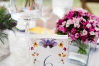 03 a bright pressed flower wedding table number with yellow, orange and lilac blooms is a cool idea for a bold garden wedding