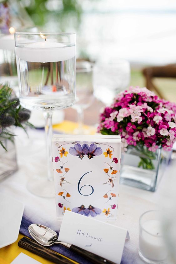 a bright pressed flower wedding table number with yellow, orange and lilac blooms is a cool idea for a bold garden wedding