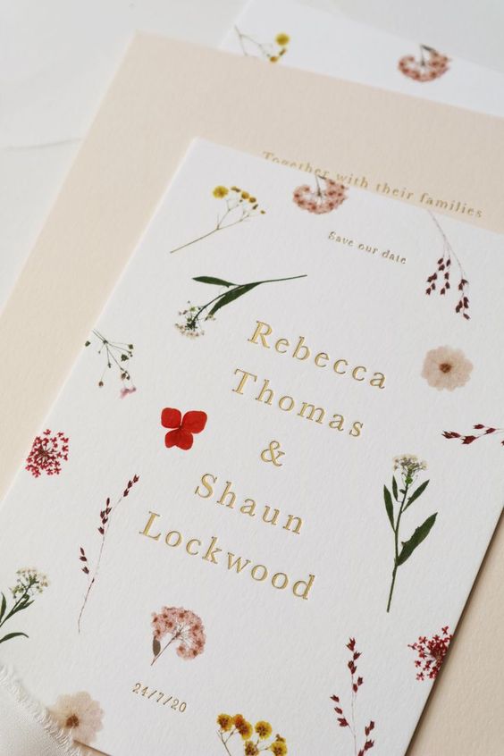 a gorgeous pressed flower and leaf wedding invitation with yellow, red and pink blooms is a lovely solution to rock