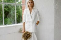 10 a chic and minimalist bridal look with an oversized white blazer and a maxi pleated skirt plus a grass wedding bouquet and statement earrings