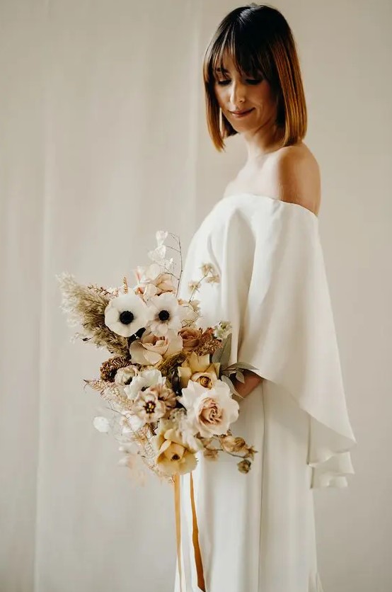 a lovely minimalist winter bridal outfit with an off the shoulder plain wedding dress plus a pastel wedding bouquet with grasses