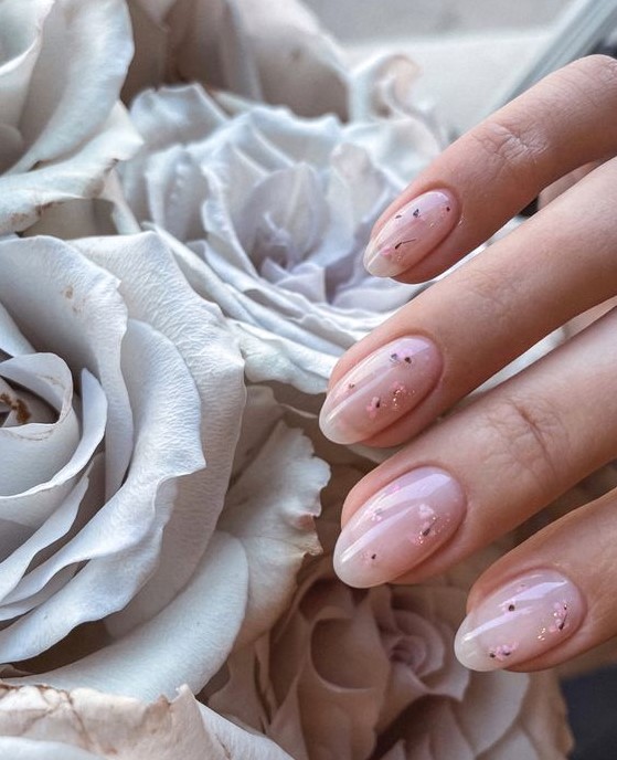 a subtle blush manicure with semi sheer gel and light pink dried blooms and gold glitter touches is amazing for spring