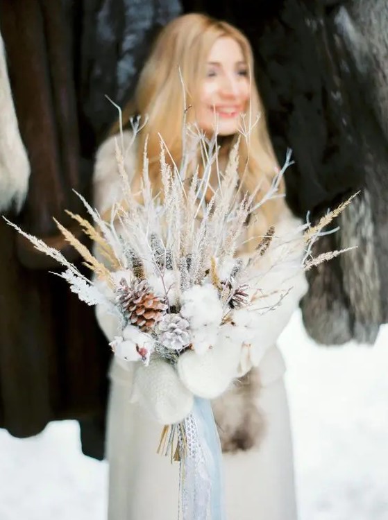 a unique frozen winter wedding bouquet with cotton, snowy branches, twigs and grasses is a great idea for a winter bride