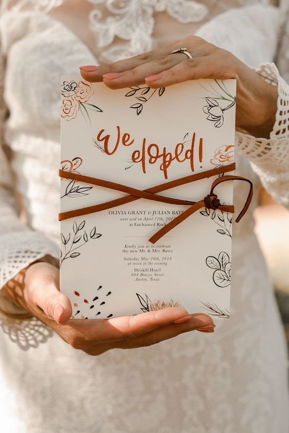 a cool boho elopement announcement with fun calligraphy, botanical prints and leather cord on it