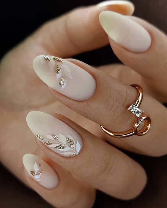 matte milky nails accented with white and blush botanical patterns and gold glitter are amazing for a glam bride