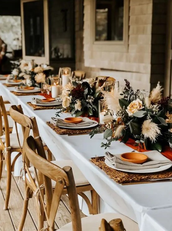 a beautiful fall backyard elopement table setting with woven placemats, neutral linens, pastel blooms, greenery and pampas grass plus candles