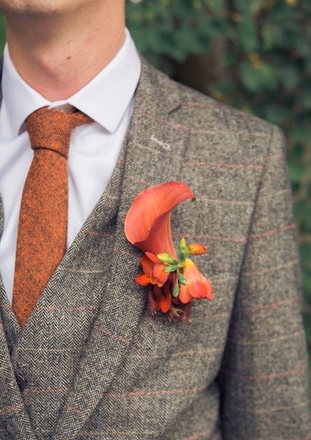 a stylish grey three-piece plaid suit, a white shirt, an orange tie and a calla boutonniere are a lovely look for the fall