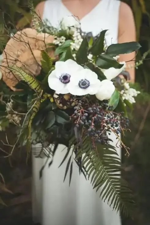 an eye catchy woodland wedding bouquet with white blooms, privet berries, foliage and twigs is a very catchy dimensional piece
