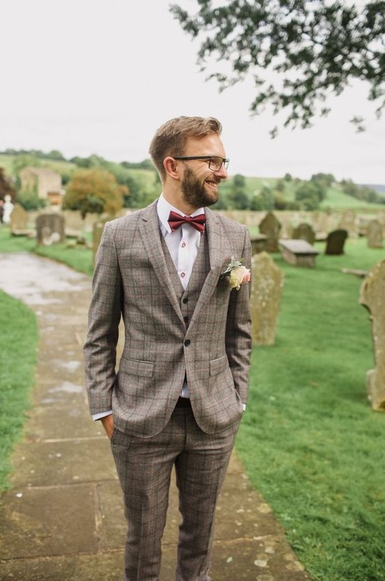 a stylish plaid beige three piece suit, a white shirt with copper buttons, a burgundy bow tie