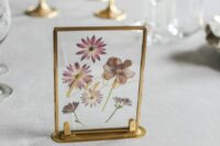 19 a beautiful glass table number with pressed flowers, a gold frame and gold calligraphy is a chic idea