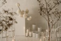 20 a jaw-dropping minimalist winter wedding space with white blooms, vases, dried branches and pillar candles