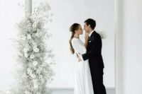 21 a minimalist wedding altar of a doorway decorated with ethereal white blooms, blooming branches and baby’s breath is a gorgeous solution