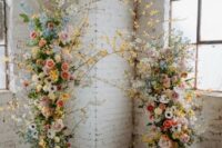 22 a colorful floral wedding arch decorated with pink, blue and neutral blooms, greenery and blooming branches is amazing