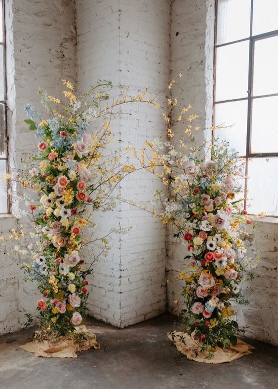 a colorful floral wedding arch decorated with pink, blue and neutral blooms, greenery and blooming branches is amazing