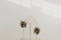 22 a minimalist wedding ceremony space with a geo wedding arch with pink floral arrangements, ghost chairs and pillar candles lining up the aisle