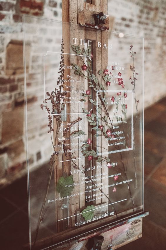 an acrylic bar menu with pink and purple pressed flowers and greenery is a fantastic solution for a boho wedding