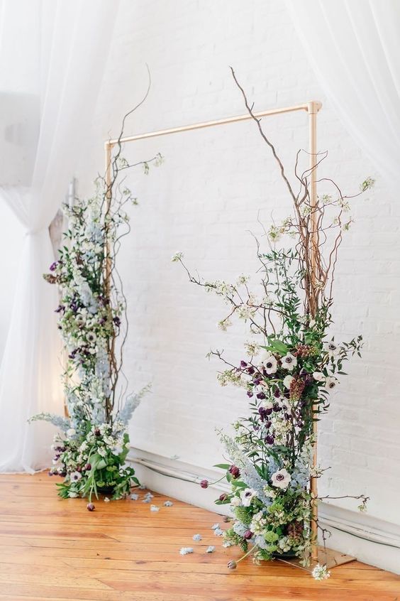 a copper wedding arch decorated with branches, white anemones and purple blooms and lots of greenery is pure beauty