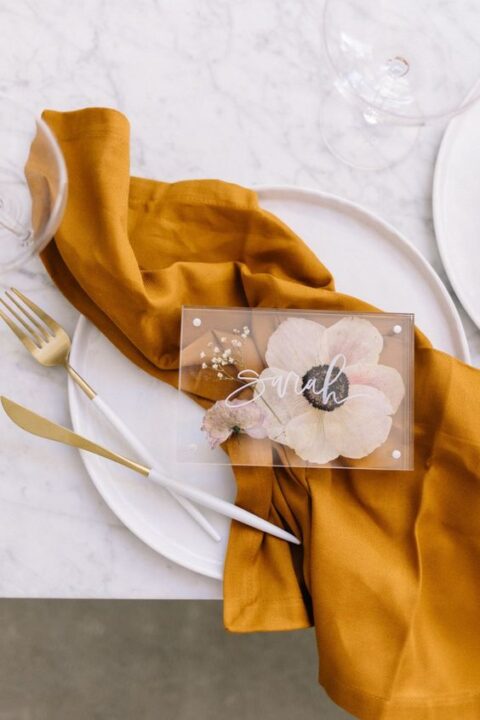 a fabulous wedding seating card with pressed blooms and white calligraphy is a very chic solution