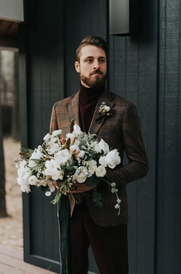 burgundy velvet pants and a matching turtleneck, a brown plaid blazer and a boutonniere for a casual winter groom's look