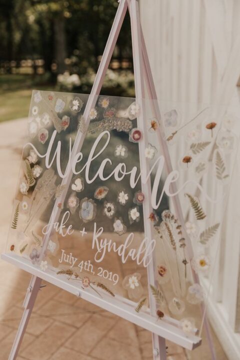 a beautiful wedding sign with white calligraphy and pressed blooms and leaves is a gorgeous idea for a spring or summer wedding