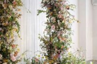28 a jaw-dropping garden wedding arch covered with greenery, yellow, blush and white blooms and some arrangements at the base looks fantastic