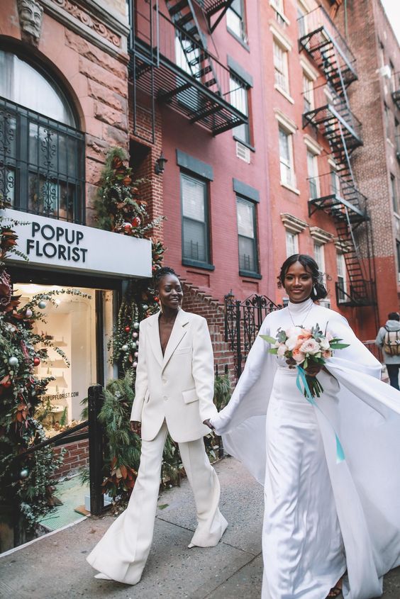 brides wearing an oversized pantsuit and a turtleneck with a maxi skirt and a capelet for a post elopement party